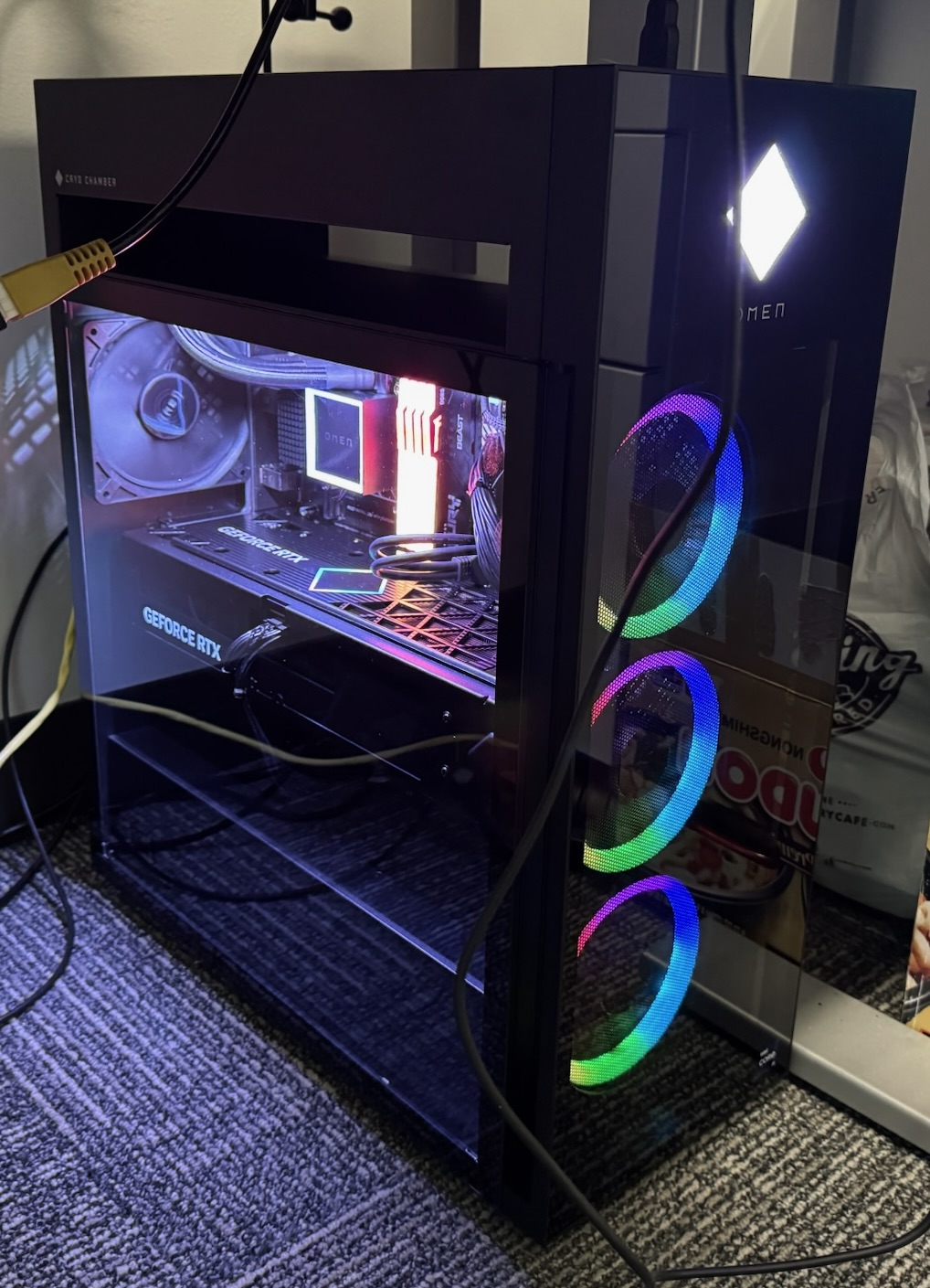 A large black gaming tower with three glowing RGB circles around fans on the front, and a bright white diamond logo.